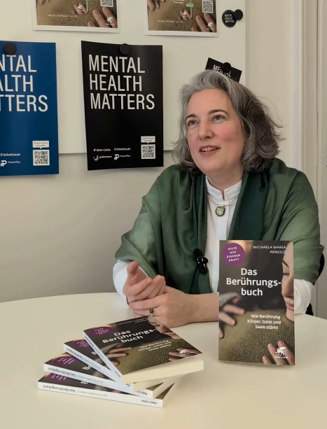 Dr. med. Michaela Maria Arnold mit Buchstapel bei einer Lesung